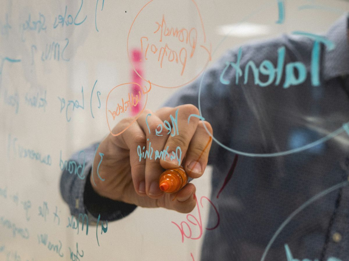 PErson writing a digital marketing strategy on a transparente board